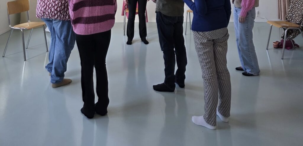 Meerdere mensen staan in een familieopstelling, op de foto zijn de benen vooral zichtbaar.